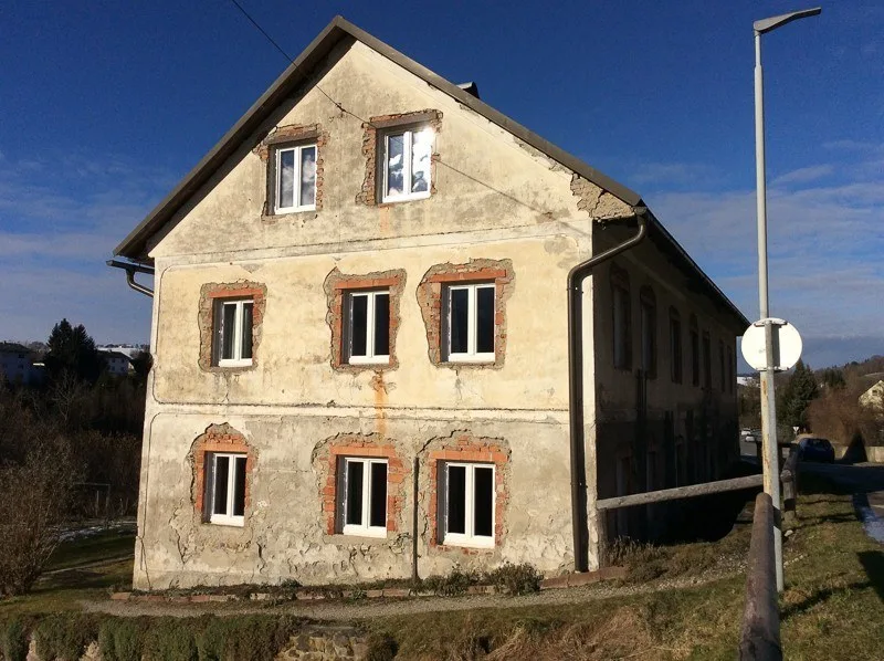 Altes zweistöckiges Haus mit abgeschlagenem Putz rund um die Fenster