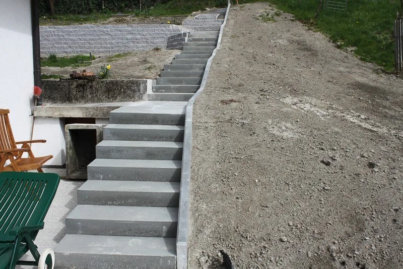Neue Betonstiege an einem Hang neben einem Haus