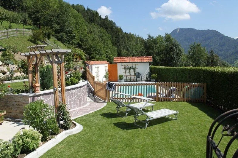 Garten mit Pool, Pergola und Liegestühlen vor Bergkulisse
