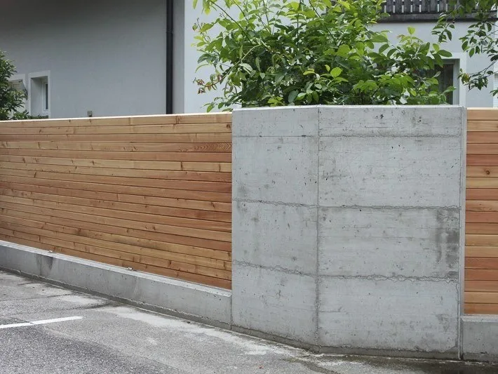 Sichtbetonmauer mit Holzlattung an einer Einfahrt
