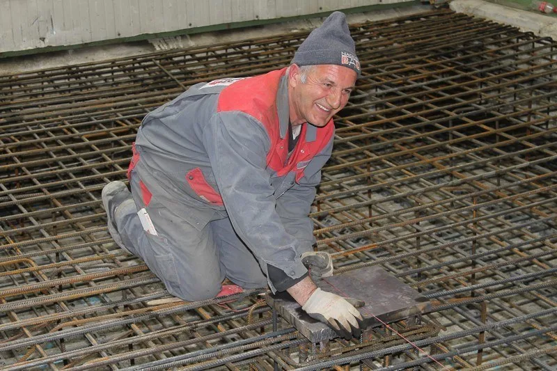 Mitarbeiter von Nagler Bau kniet lachend auf der Bewehrung einer Bodenplatte