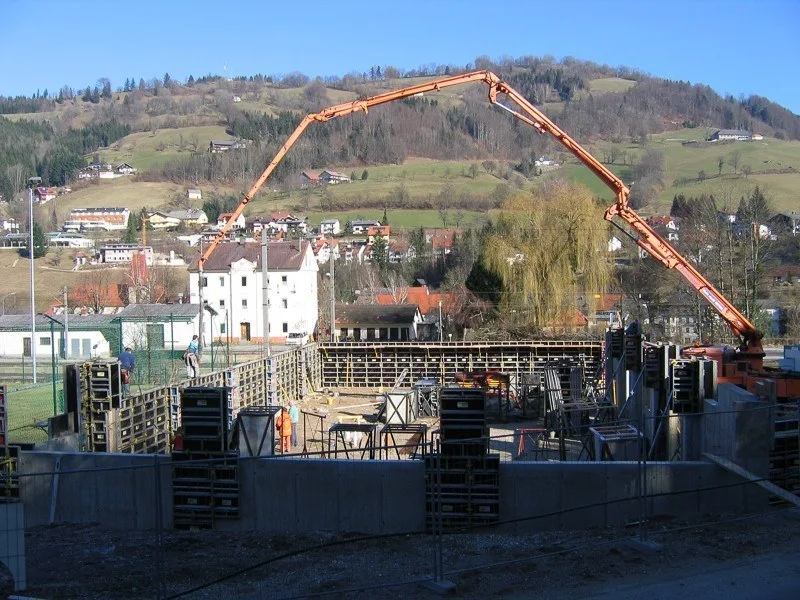 Betonpumpe über der Schalung einer Baustelle, Hügel im Hintergrund