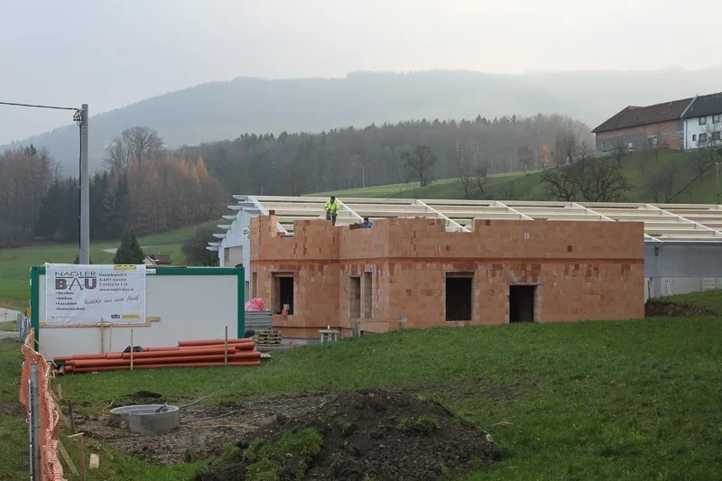 Ziegelrohbau eines Hauses mit der Bautafel von Nagler Bau im Vordergrund