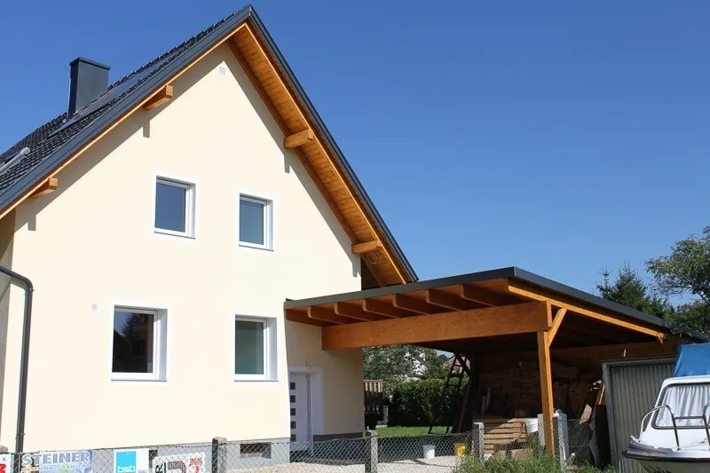 Dasselbe Wohnhaus mit Carport nach der Sanierung mit heller Fassade