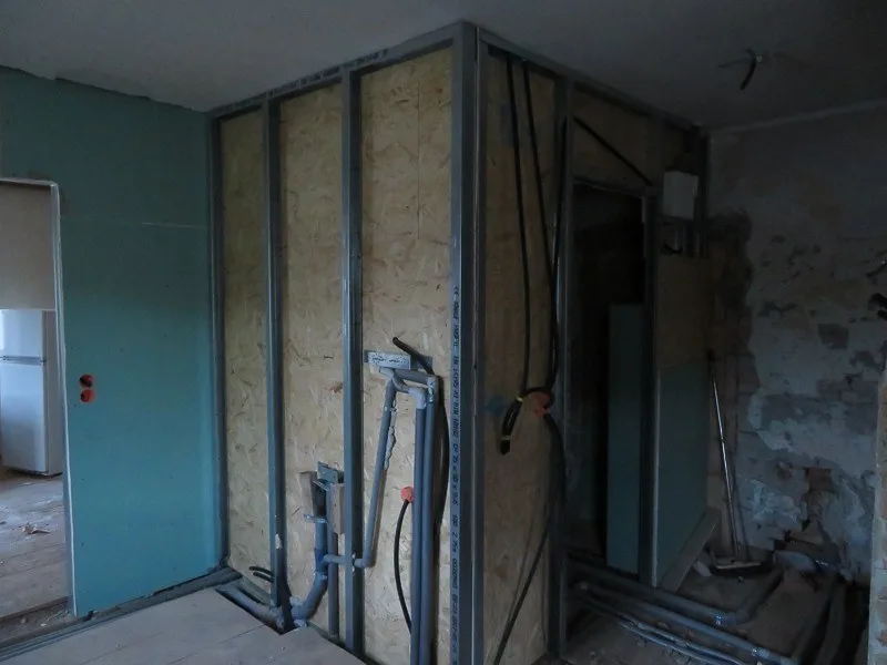 Metallständerwand mit Platten und offenen Installationen in einem Raum
