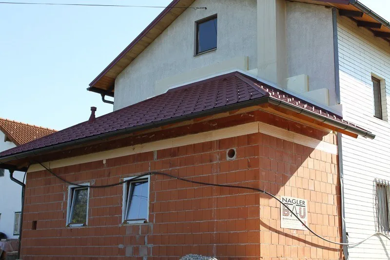 Zubau aus Ziegeln an einem Wohnhaus mit der Bautafel von Nagler Bau